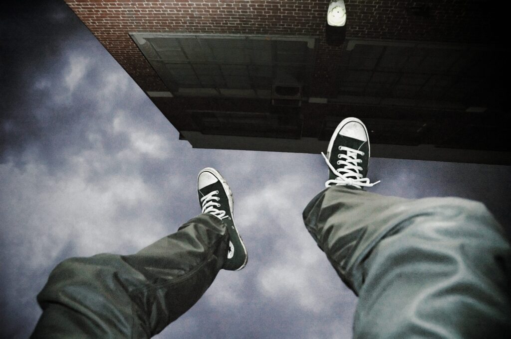 Photograph of a persons legs hanging over a building